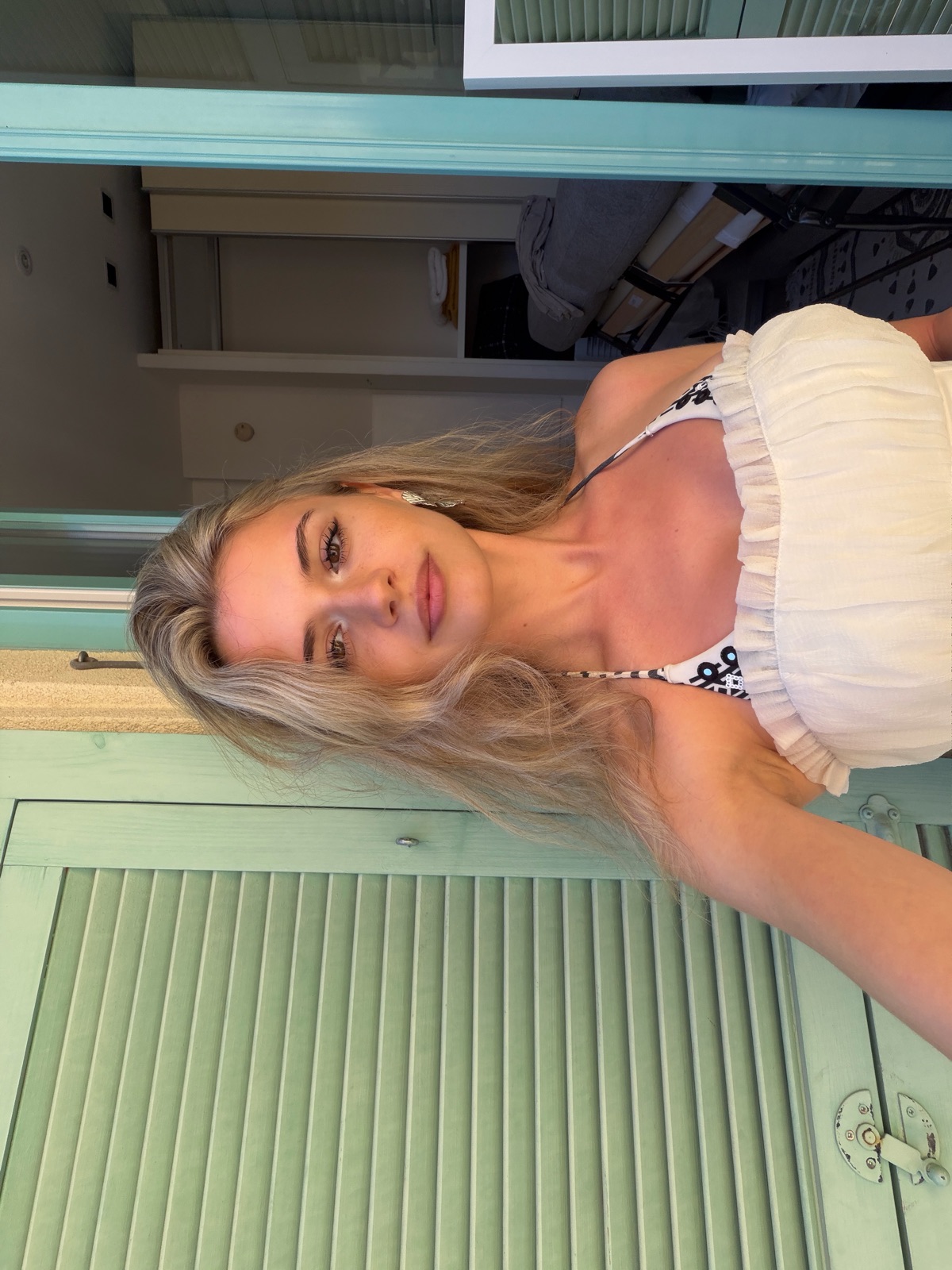 Yana smiling by a window with mint-green shutters