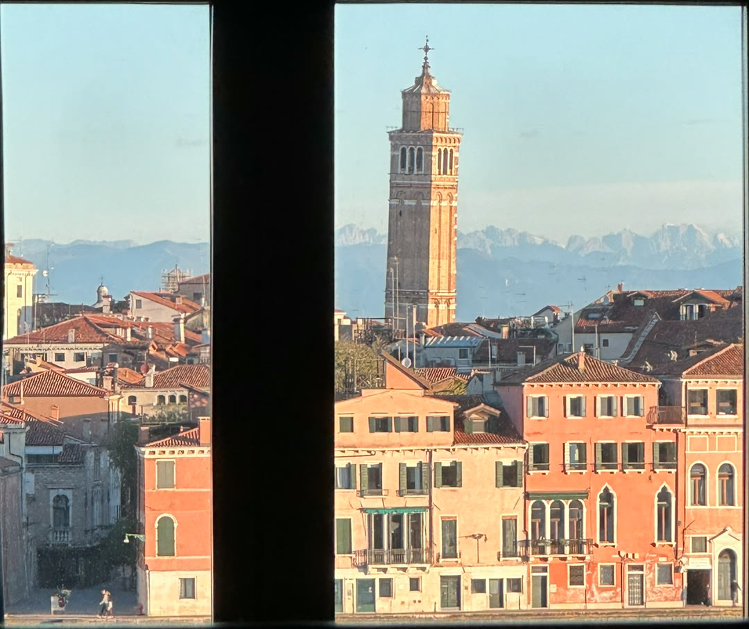 Venice rooftops and a bell tower seen through a dark window frame
